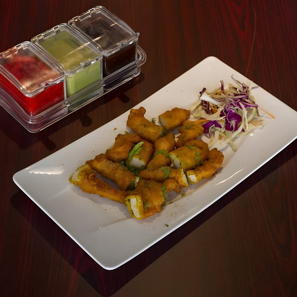 Curry Mantra's golden-fried chicken pakora with a side of cabbage salad and three dipping sauces.