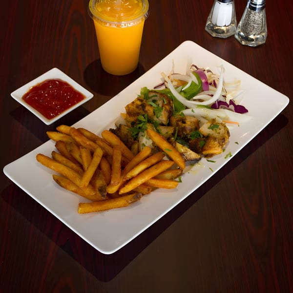 Curry Mantra's Indian chicken tikka, fries, salad, ketchup, and mango lassi on a wooden table.